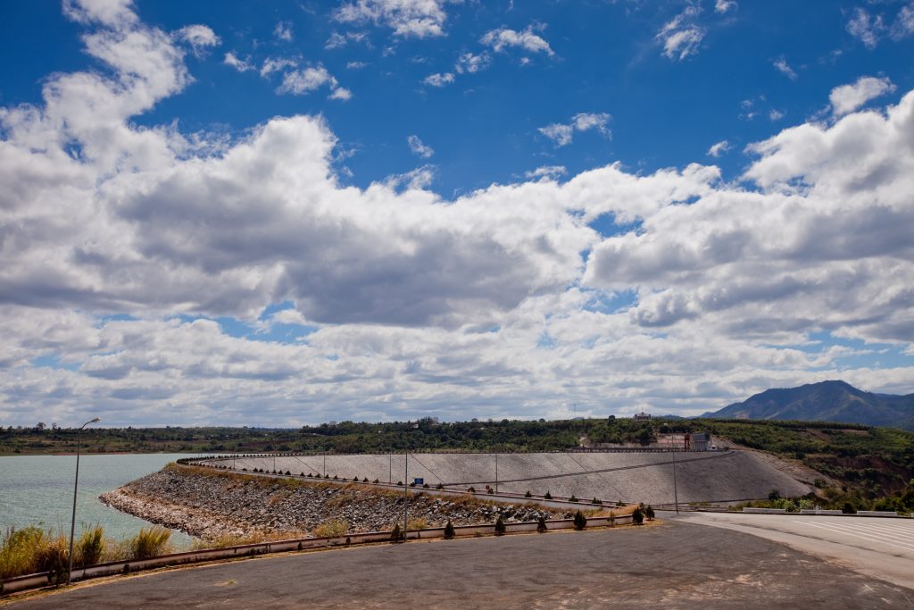 The Mekong river flowing past a hydropower dam with dry banks visible in the foreground