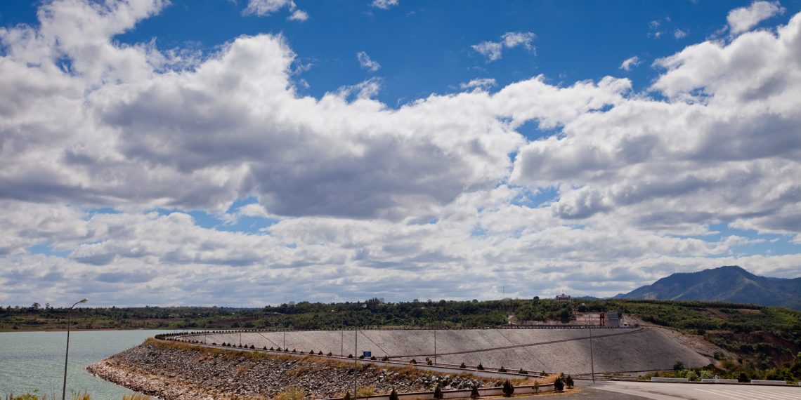 The Mekong river flowing past a hydropower dam with dry banks visible in the foreground